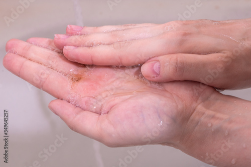 Woman washes her hands with liquid soap - closeup