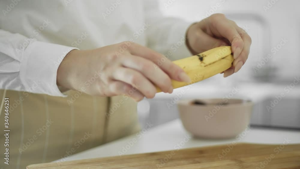 Close up of girl cleans the banana peel in the kitchen Close up of girl cleans the banana peel in the kitchen