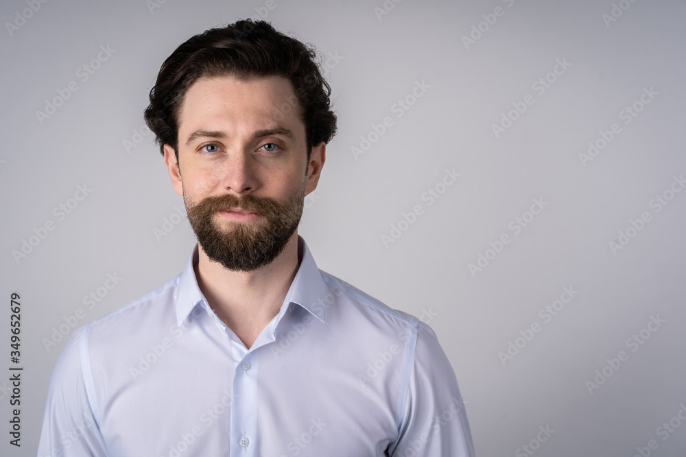 The portrait on the chest young man with a beard in a white shirt, he smiles and looks straight into the camera The portrait on the chest young man with a beard in a white shirt, he smiles and looks straight into the camera