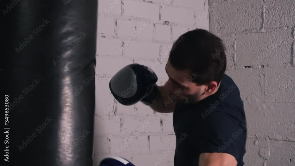 Professional boxer training at gym. Focused fighter boxing punching bag. Sport, workout, martial arts concept Professional boxer training at gym. Focused fighter boxing punching bag. Sport, workout, martial arts concept