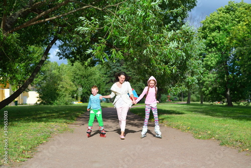 Woman leads by the hand of children on roller skates in the Park in St. Petersburg