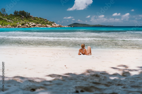 Young tanned woman enjoying tropical sandy beach Anse Cocos at La Digue Island, Seychelles