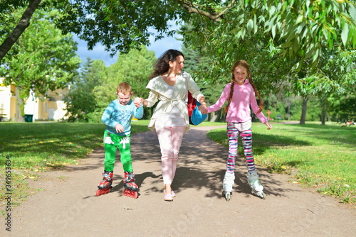 Woman rolls children's hands on roller skates in a Sunny Park in the summer in St. Petersburg