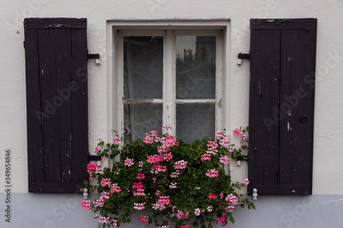 Very old window with wooden shutters and flowers