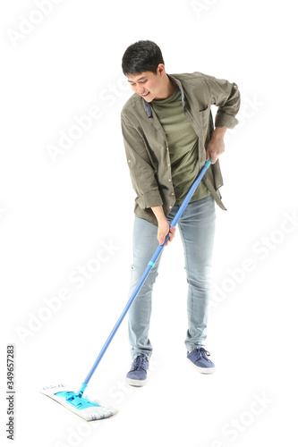 Young Asian man with mop on white background