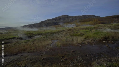 Green valley with hot springs. Steam rises above lakes and streams photo