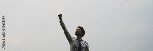 Behang Wide view image of successful young businessman standing under cloudy sky