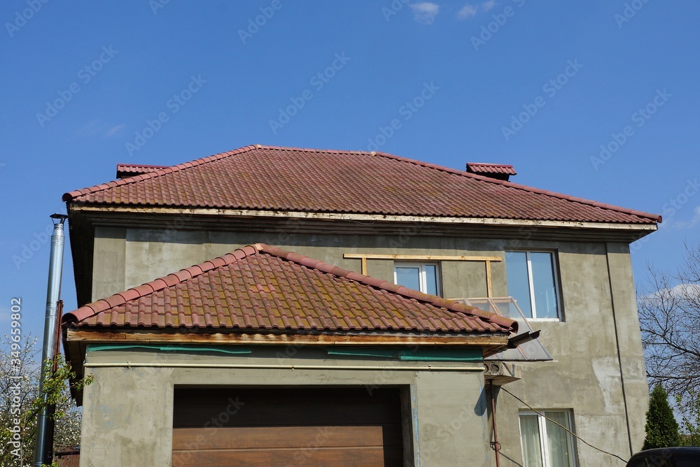 private gray house with windows under a brown tiled roof against a blue sky private gray house with windows under a brown tiled roof against a blue sky
