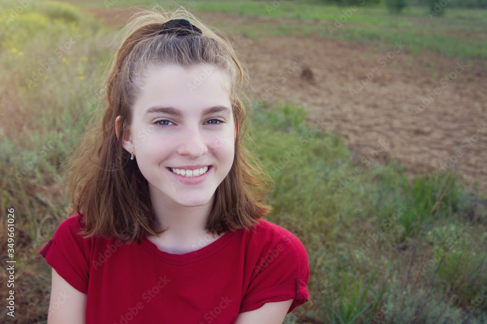 Portrait of a beautiful young teenage girl with a joyful smile in the field outdoors. Copyspace. Portrait of a beautiful young teenage girl with a joyful smile in the field outdoors. Copyspace.