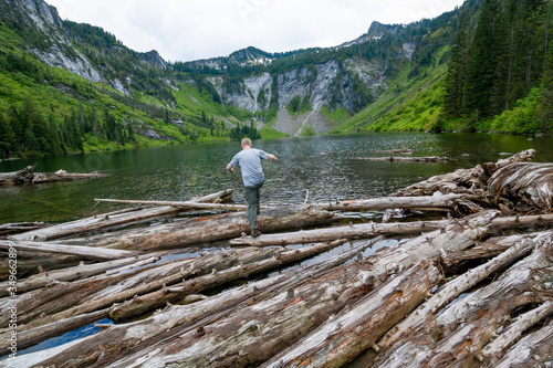 Adventurous male hiker climbing over driftwood at an alpine lake in Washington State.  © Pelo Blanco Photo