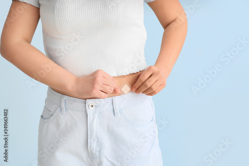 Young woman with contraceptive patch on color background