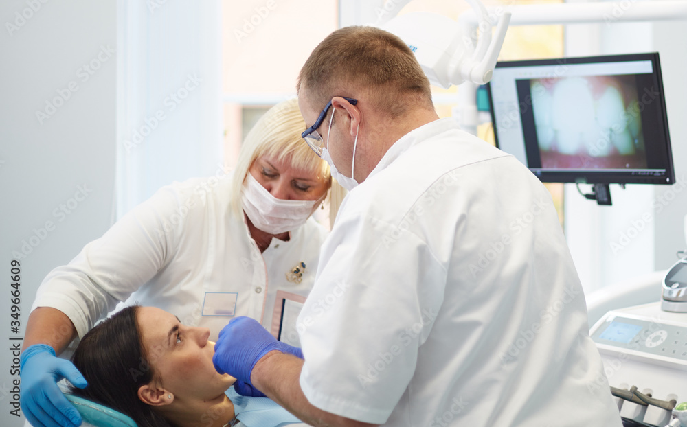Obraz premium Doctor dentist treats teeth of a beautiful young girl patient.