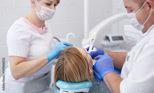 Doctor dentist treats teeth of a beautiful young girl patient.