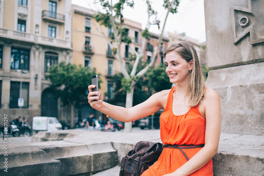 Satisfied traveling female taking selfie on smartphone during sightseeing