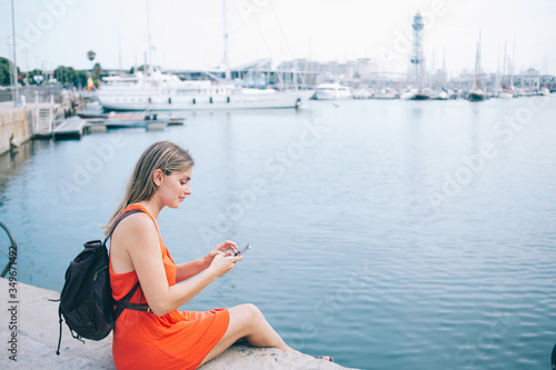 Calm traveling woman browsing smartphone in port