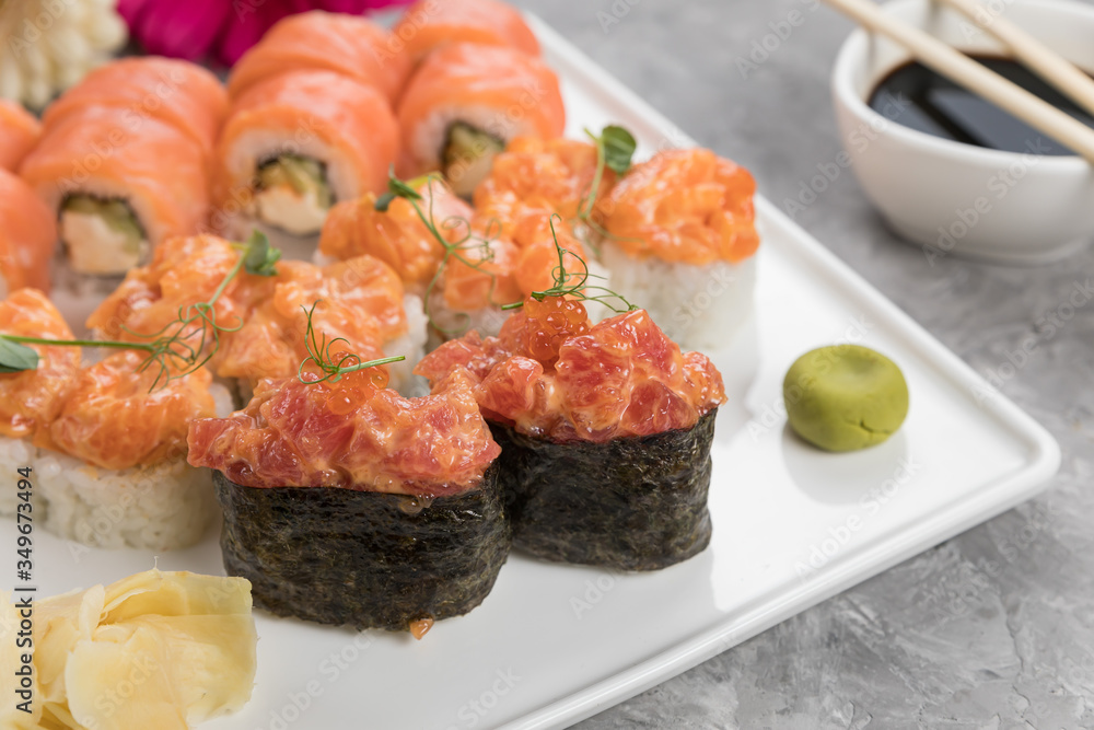 Assorted rolls with sauce and chopsticks on a gray background
