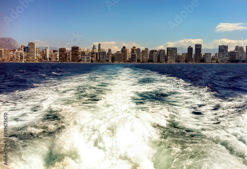 Image of a city full of buildings, seen from a boat moving away from it at high speed. Concept of distance, beauty and distance.