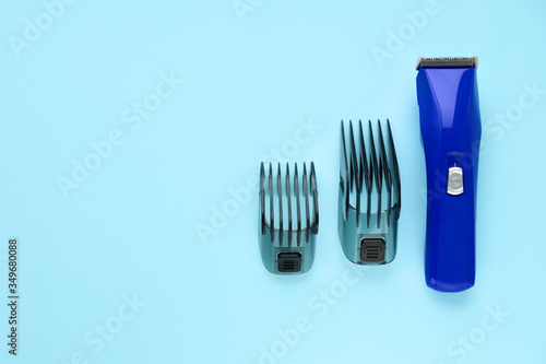 Blue hair clipper with two attachments on a blue background. Space for text. Selective focus. Tools for working as a hairdresser. Copy space