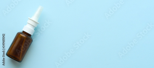 Nasal spray in a glass bottle on a blue background.Space for text. Selective focus. Spray for the treatment of runny nose and allergies. Copy space