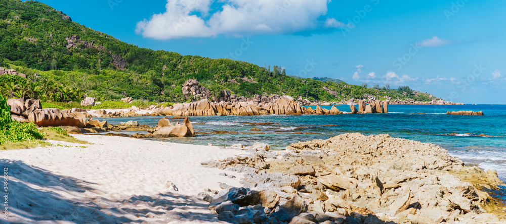La Digue, Seychelles. Panoramic view of beautiful secluded beach, tropical ocean coastline, unique granite rocks and jungle in background