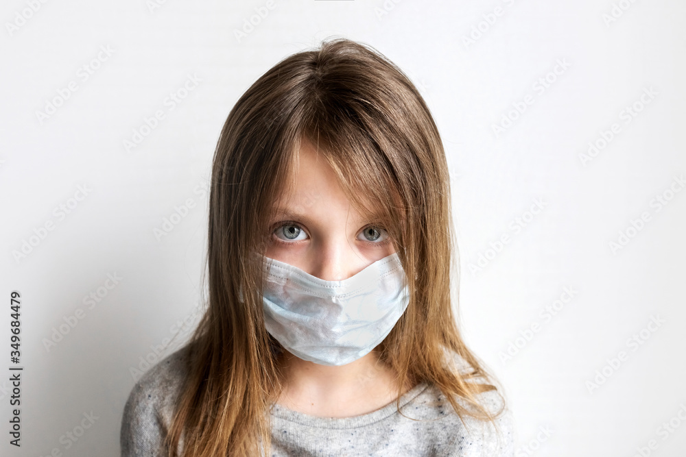 Stay at home in quarantine coronavirus pandemic. Sad child in protective medical mask. Prevention epidemic. Close-up portrait of a little girl in a medical mask looks at the camera on white background Stay at home in quarantine coronavirus pandemic. Sad child in protective medical mask. Prevention epidemic. Close-up portrait of a little girl in a medical mask looks at the camera on white background