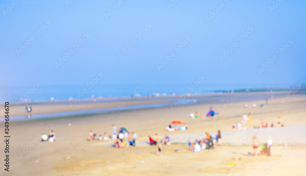Landscape of blurry crowd of people sitting and lying down on the sand beach, Blurred image of People enjoy swimming in a sunny day at tropical beach, Summer holiday concept.