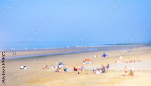 Landscape of blurry crowd of people sitting and lying down on the sand beach, Blurred image of People enjoy swimming in a sunny day at tropical beach, Summer holiday concept. © Anchalee