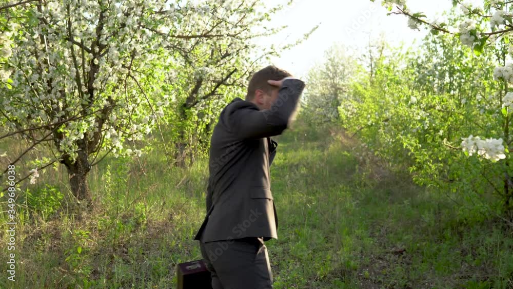 A businessman walks through the apple orchard and looks around. A man in a suit looks at his possessions. A man in nature. A businessman walks through the apple orchard and looks around. A man in a suit looks at his possessions. A man in nature.