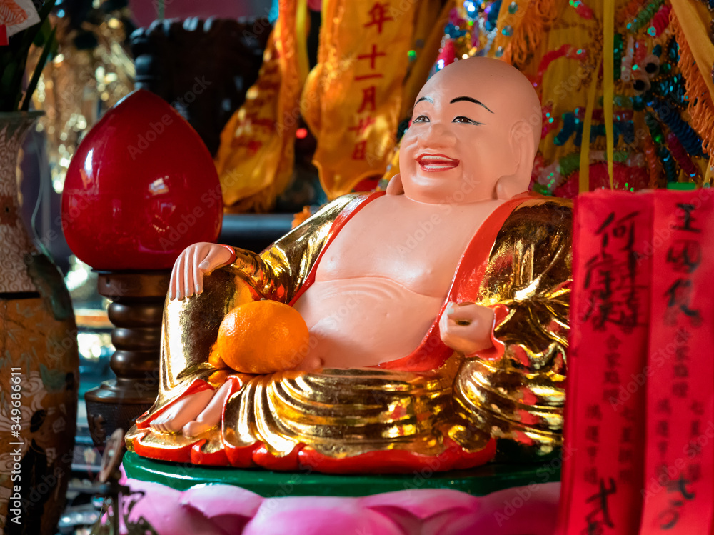 Happy smiling buddha statue with orange donation in temple