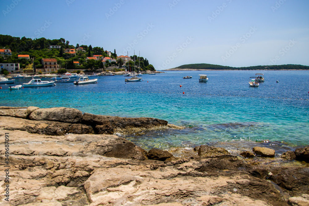 View of the Pakleni islets from Hvar island in Croatia - Small boats anchored in a bay in the Adriatic Sea with a house-covered peninsula