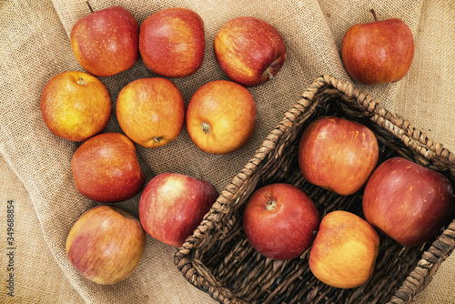 Fresh red apples in wicker basket on rustic background, close up, view from above