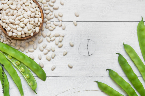 Uncooked dried white haricot beans in bowl with fresh raw green beans pod plant on rustic table. Heap of legume haricot bean background ( Phaseolus vulgaris ) photo