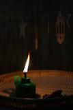 Oil lamp with flaming fire on woven tray with ketupat ornaments