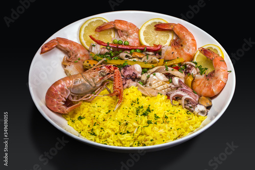 Seafood paella, on white platter, on black background