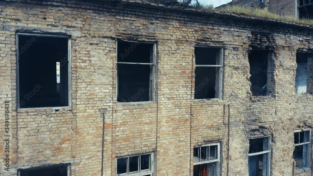 Abandoned old building ruins with broken windows. Old industrial edifice for demolition. Aerial side view