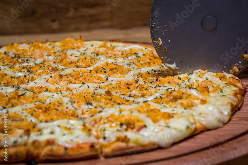 cutting the chicken pizza with Catupiry cheese,in Brazil it is called chicken pizza with catupiry cheese photo