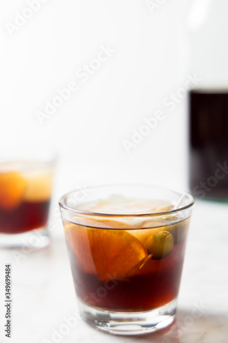 Glasses of red vermouth with orange slice and olive. Bottle as background