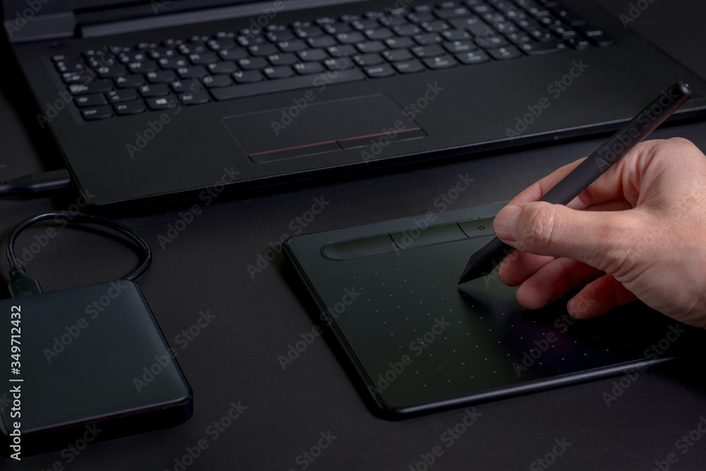 Hand drawing on a pen tablet with a laptop and a hard drive on a black background Hand drawing on a pen tablet with a laptop and a hard drive on a black background