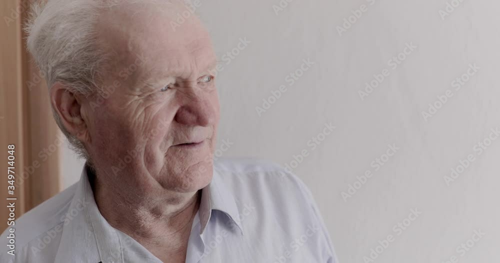 Older man looks out window and rejoices at camera during self-isolation at home Older man looks out window and rejoices at camera during self-isolation at home