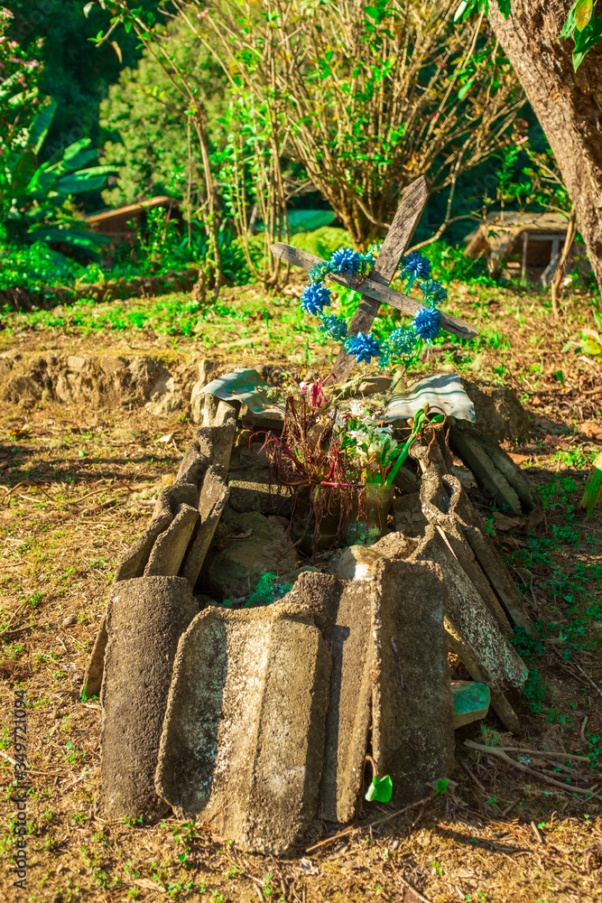 Clandestine Tomb with a Cross, Stones and Cement Tiles Surrounding it on a Green Hill Clandestine Tomb with a Cross, Stones and Cement Tiles Surrounding it on a Green Hill