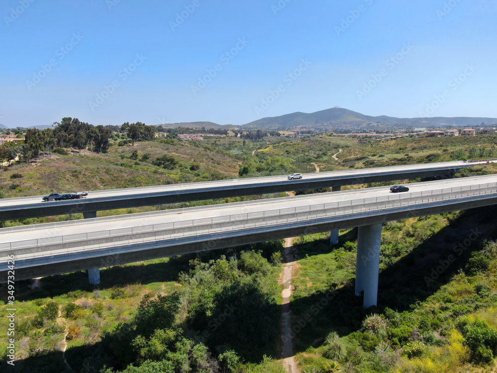 Aerial view of road highway bridge, viaduct supports in the valley among the green hills, transport infrastructure. California, USA Aerial view of road highway bridge, viaduct supports in the valley among the green hills, transport infrastructure. California, USA