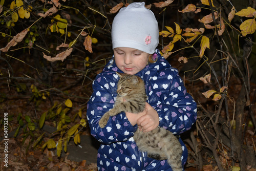 The girl is holding her beloved pet cat in her arms.