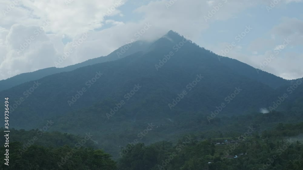Camera is flying through garden in asian tropics in front of green mountain. Early evening. Slow motion. Camera is flying through garden in asian tropics in front of green mountain. Early evening. Slow motion.