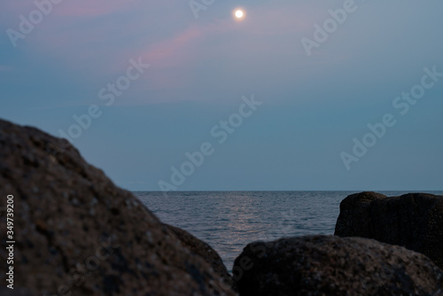 Full moon at spectacular sunset over rocks and sea