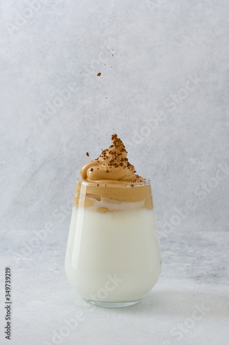 Whipped dalgona coffee concept. Instant coffee is pouring on foam in glass. Instant coffee or espresso powder whipped with sugar and hot water. 