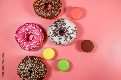 Tasty donuts and macaroons on pink background. Top view
