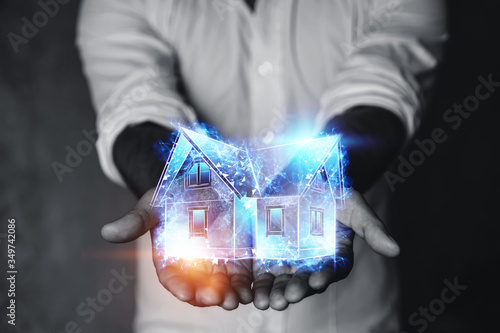 Mortgage concept for housing mortgage interest rates. A man holds a hologram of a house and a percent sign on his hand. Copy space, mixed media.