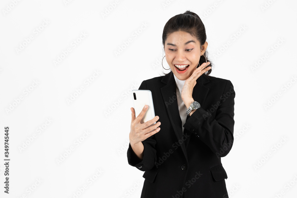 Shocked happy young Asian business woman in suit looking at mobile smart phone over white isolated background. Shocked happy young Asian business woman in suit looking at mobile smart phone over white isolated background.