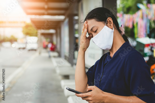 woman wearing mask getting headache and using smartphone in the city.