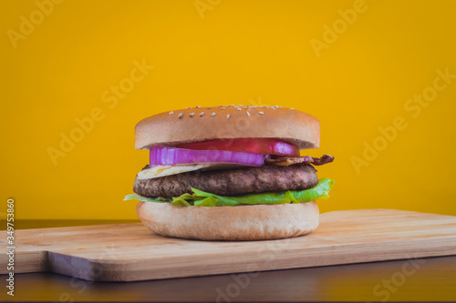 HAMBURGUESA CON TOCINO Y QUESO EN FONDO AMARILLO